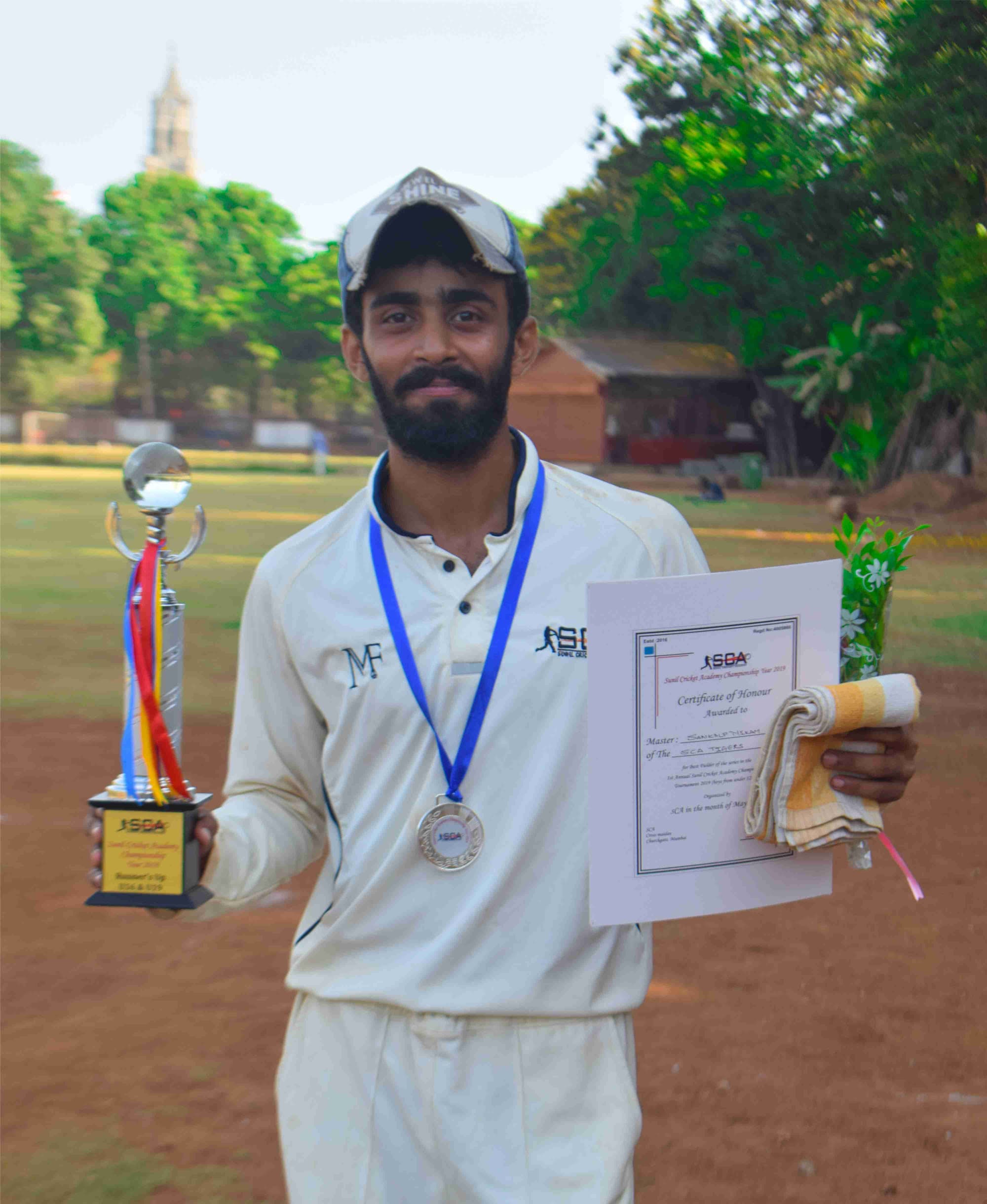 A player with his trophy, medal and winner’s certificate