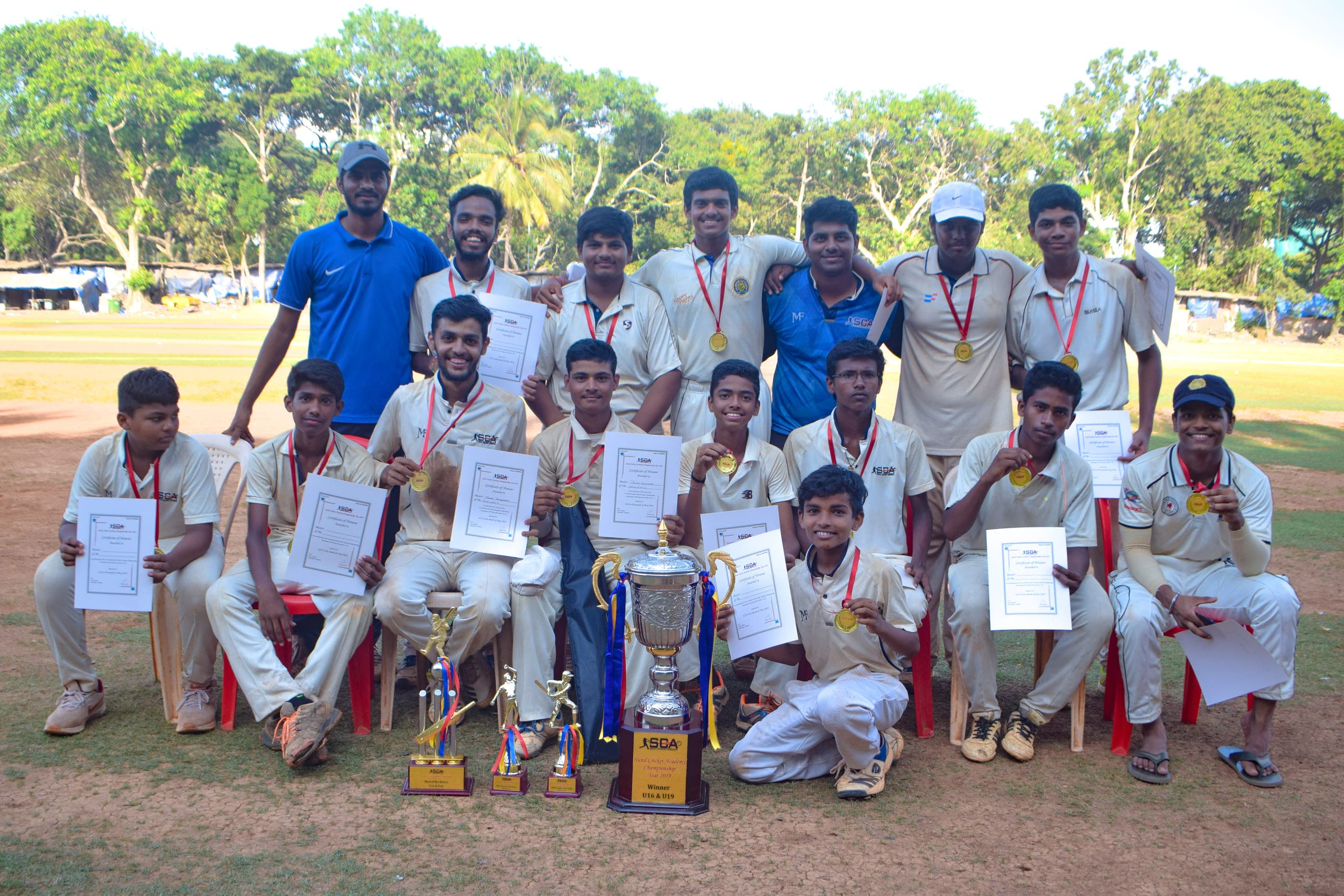 Sunil Cricket Academy squad with the SCA Championship trophy, medals and certificates